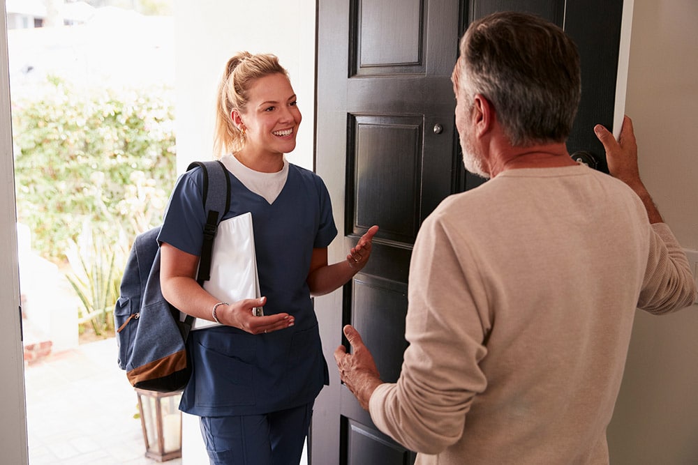 Man opening his front door to a female healthcare worker making a home health visit