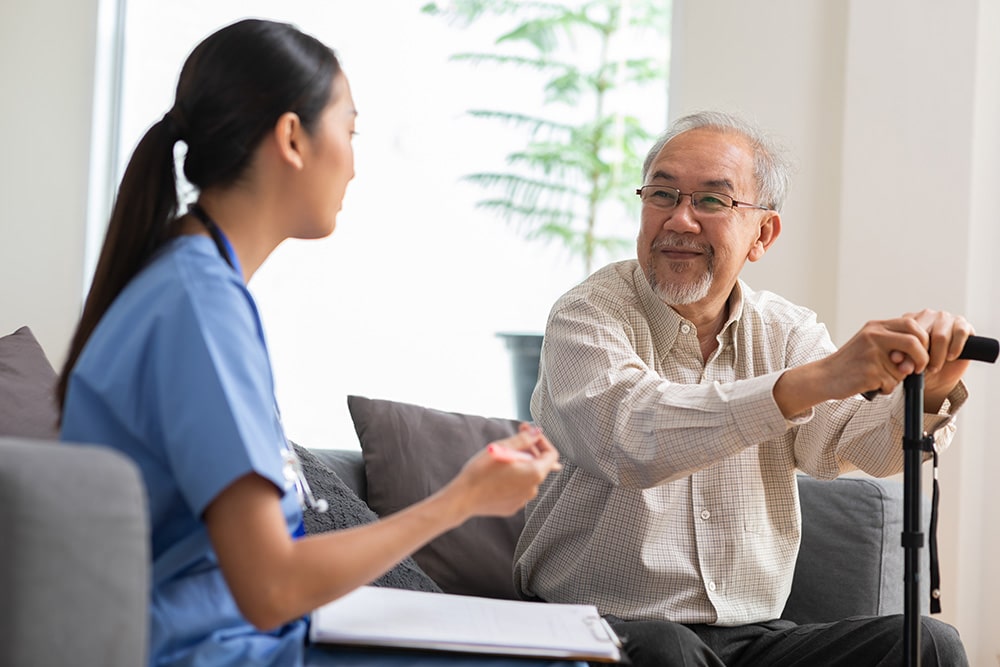 Patient talking to caring female doctor physician at home