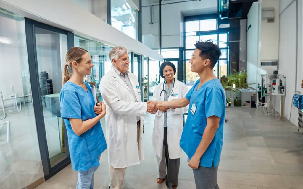 Healthcare, doctor and nurse shaking hands in a hospital